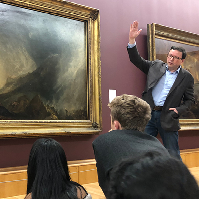 Professor gesturing to class in art museum