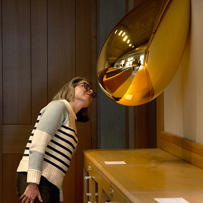 Woman examining metallic sculpture on wall